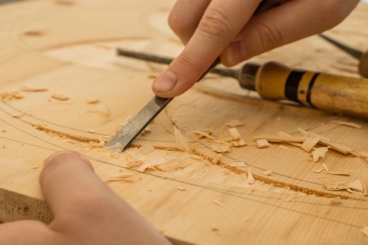 Hands carving a furniture component from wood with a chisel